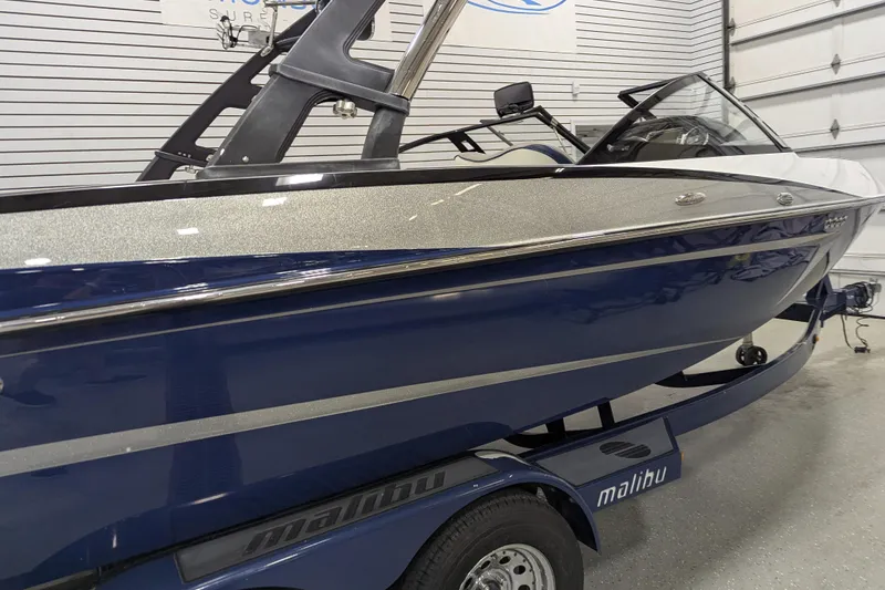 Slide: The Image of 2012 Malibu Wakesetter VLX boat in showroom, blue and silver design, on trailer. - 5