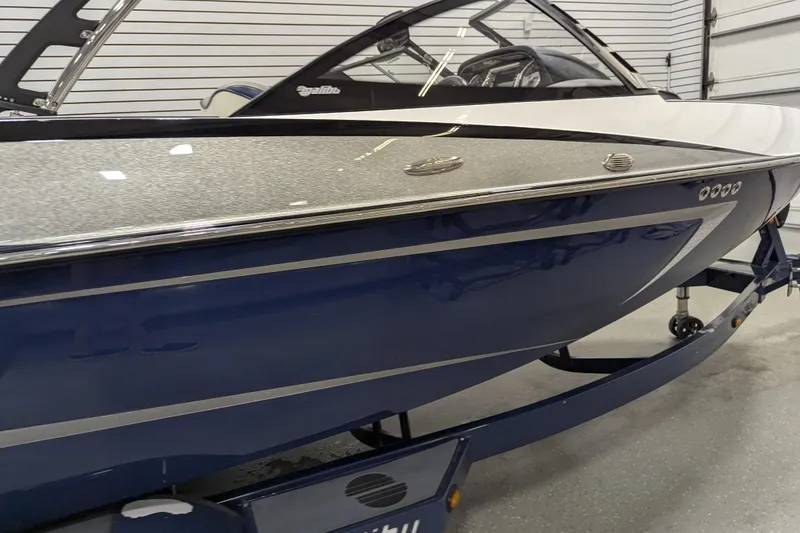 Slide: The Image of 2012 Malibu Wakesetter VLX boat in showroom, sleek design with blue and white finish. - 7