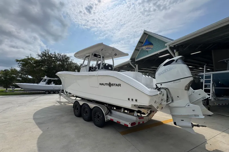 Slide: The Image of 2026 NauticStar 332 Offshore boat on trailer, featuring dual Suzuki outboard engines. - 16