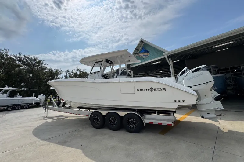 Slide: The Image of 2026 NauticStar 332 Offshore boat on trailer, parked outdoors under a partly cloudy sky. - 17