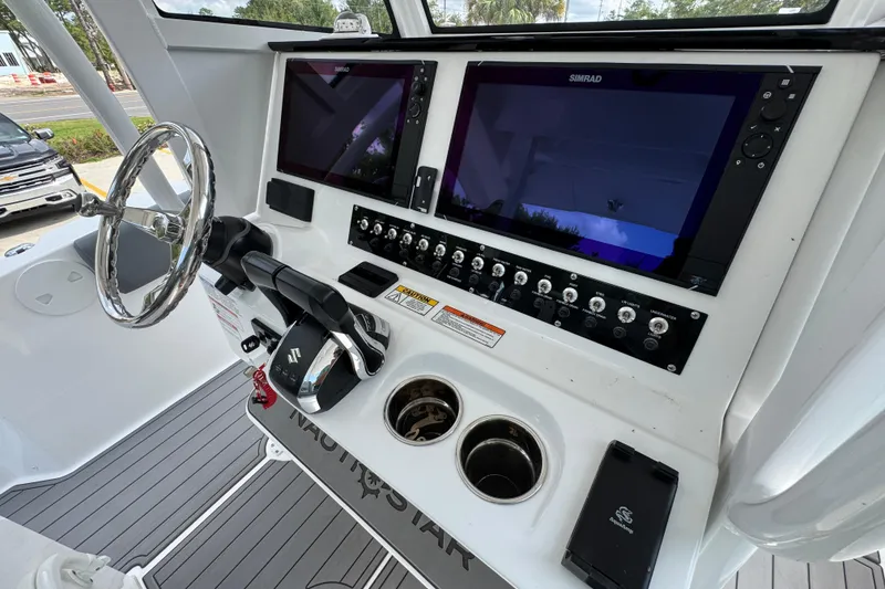 Slide: The Image of 2026 NauticStar 332 Offshore boat dashboard with dual Simrad displays and Suzuki controls. - 35