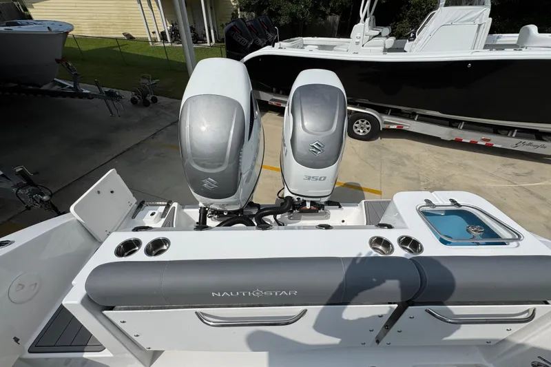Slide: The Image of 2026 NauticStar 332 Offshore boat with dual Suzuki 350 engines, docked outdoors. - 43
