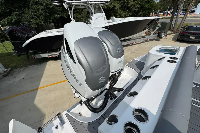 Slide: The Image of 2026 NauticStar 332 Offshore boat with dual Suzuki 350 engines, parked outdoors. - 45