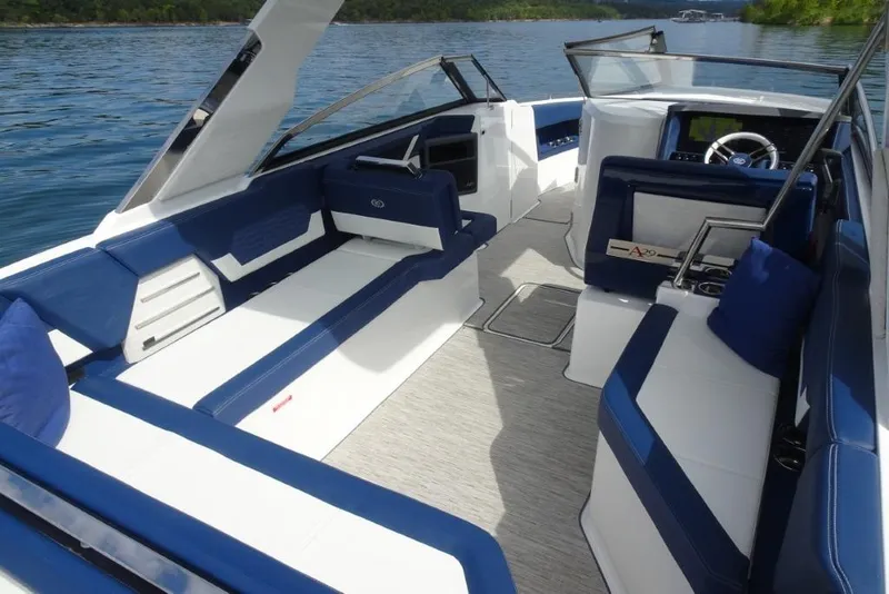 Slide: The Image of 2023 Cobalt A29 boat interior with blue and white seating, on a serene lake. - 12