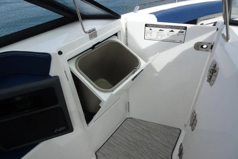Slide: The Image of 2023 Cobalt A29 boat interior with open storage compartment and trash bin. - 25