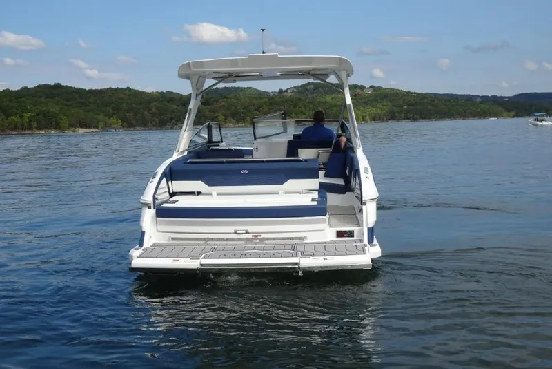 Slide: The Image of 2023 Cobalt A29 boat cruising on a serene lake with scenic forested hills. - 3