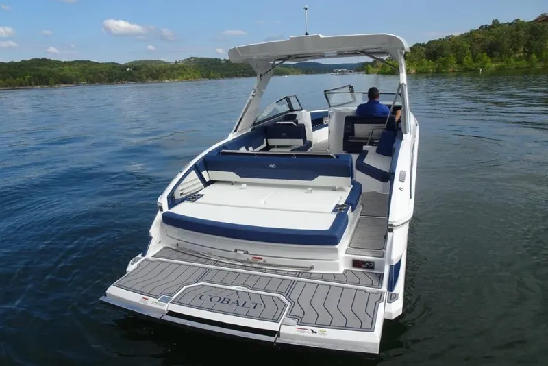 Slide: The Image of 2023 Cobalt A29 boat cruising on a serene lake with lush green shoreline. - 8