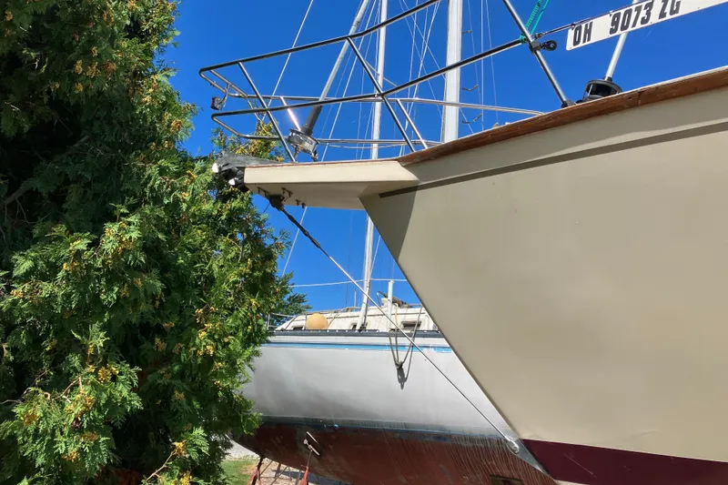 Slide: The Image of 1990 Island Packet 32 sailboat docked near lush greenery under clear blue sky. - 8