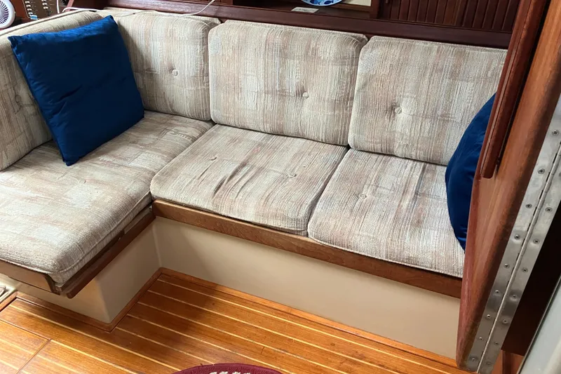Slide: The Image of Interior seating of 1990 Island Packet 32 Cutter with blue cushions and wooden flooring. - 23