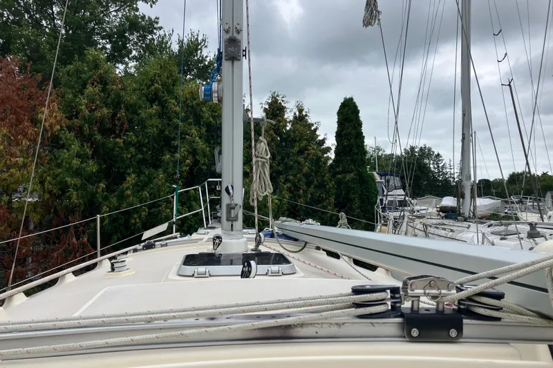 Slide: The Image of 1990 Island Packet 32 Cutter sailboat deck with rigging, surrounded by trees and other boats. - 17