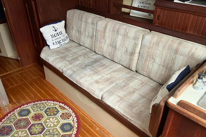 Slide: The Image of Interior of 1990 Island Packet 32 Cutter with cozy seating and nautical-themed pillows. - 22