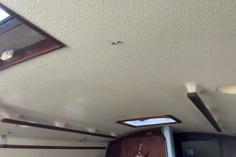 Slide: The Image of Interior ceiling of 1990 Island Packet 32 Cutter sailboat, featuring wooden accents and hatch. - 18