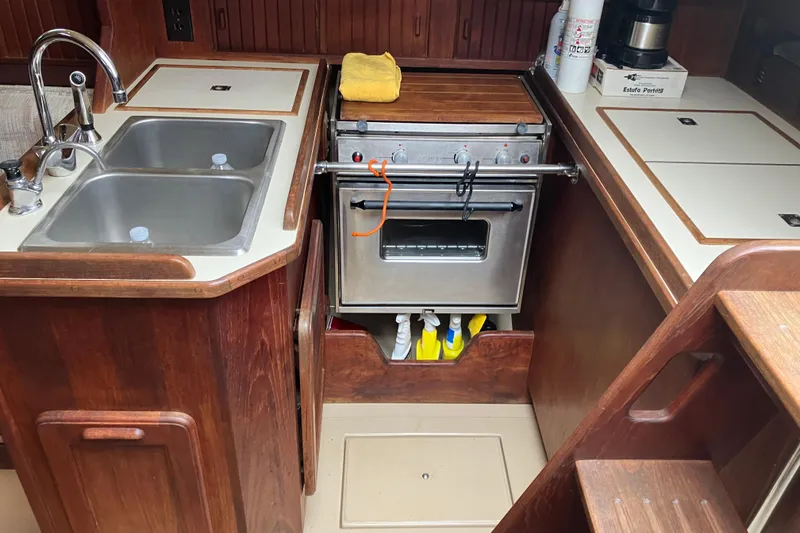Slide: The Image of 1990 Island Packet 32 Cutter galley with dual sinks, stove, and wooden cabinetry. - 31