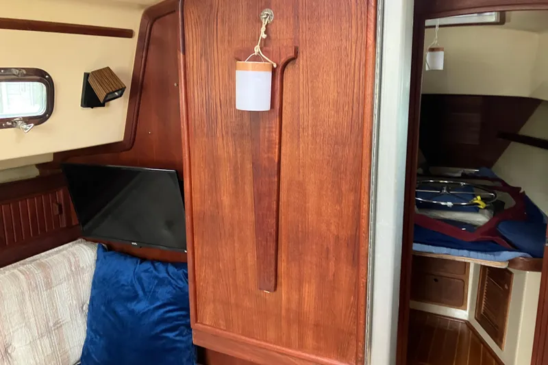 Slide: The Image of Interior of 1990 Island Packet 32 Cutter sailboat with wood paneling and cozy seating. - 25