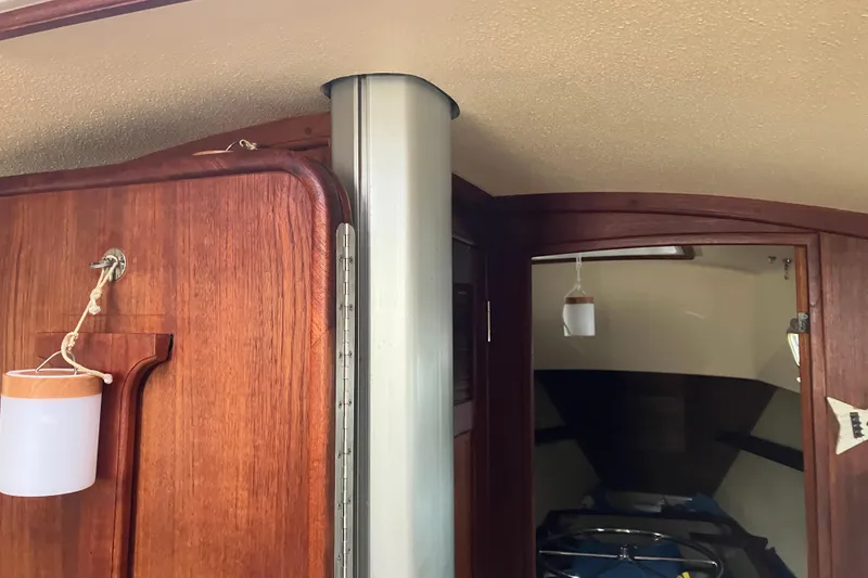 Slide: The Image of Interior of 1990 Island Packet 32 Cutter sailboat, featuring wooden cabinetry and a metal support pole. - 27