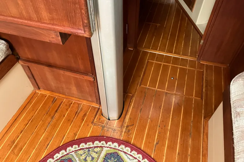 Slide: The Image of Interior of 1990 Island Packet 32 Cutter with wooden flooring and decorative rug. - 26