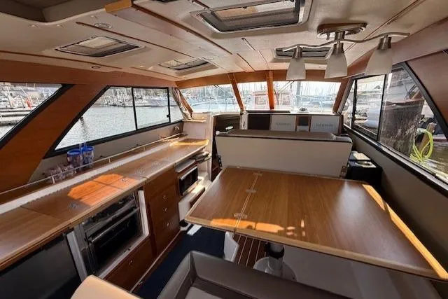 Slide: The Image of 2024 Cutwater C-30 Sedan interior with modern kitchen and dining area, docked at marina. - 10