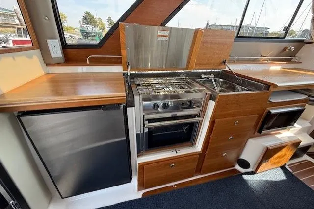 Slide: The Image of 2024 Cutwater C-30 Sedan interior kitchen with stove, sink, and refrigerator. - 11