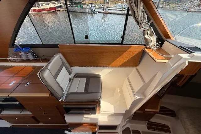 Slide: The Image of 2024 Cutwater C-30 Sedan interior with seating, wood accents, and marina view. - 13