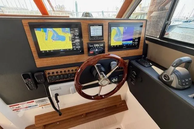 Slide: The Image of 2024 Cutwater C-30 Sedan helm with dual navigation screens and wooden steering wheel. - 15