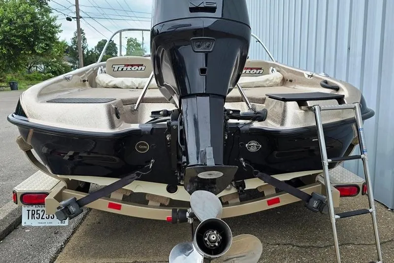 Slide: The Image of 2005 Triton SF18 F&S boat with outboard motor and trailer, parked outdoors. - 14
