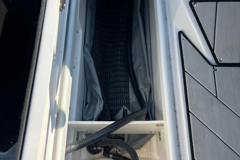 Slide: The Image of 2024 Yamaha Boats 255XD storage compartment with hoses and flooring detail. - 18