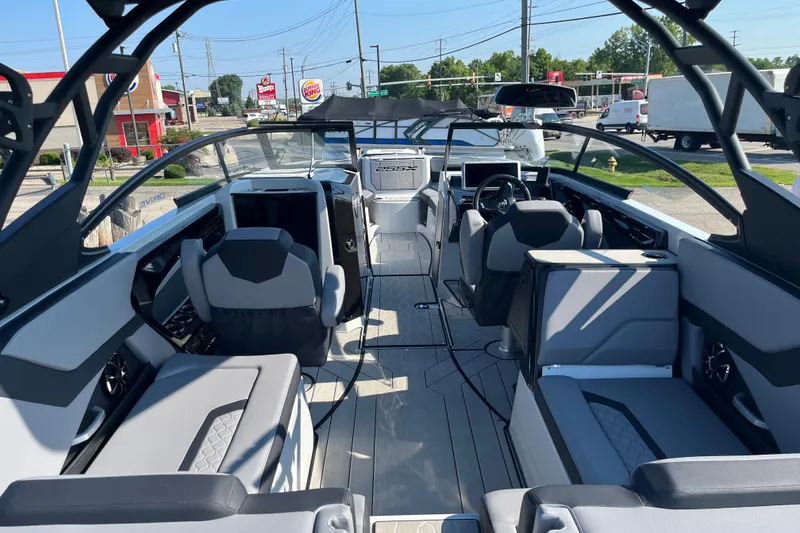 Slide: The Image of 2024 Yamaha Boats 255XD interior with modern seating and dashboard, parked outdoors. - 24
