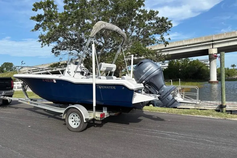 Slide: The Image of 2017 Tidewater 180 CC Adventure boat on trailer near waterway and bridge. - 2