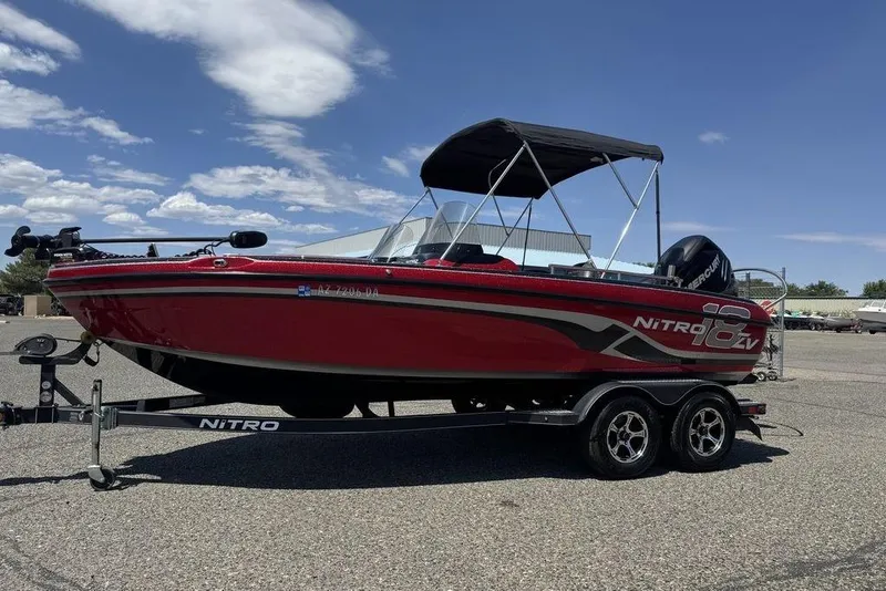 Slide: The Image of 2017 Nitro ZV18 boat on trailer, red with canopy, parked outdoors under blue sky. - 1