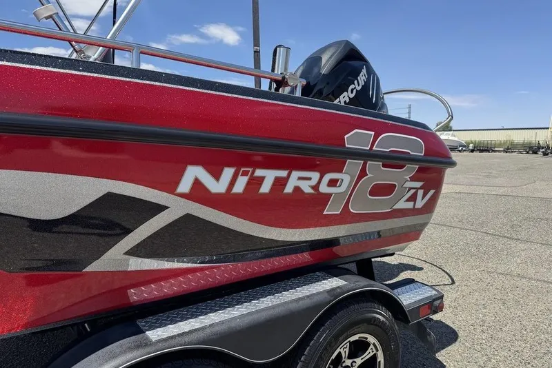 Slide: The Image of Red 2017 Nitro ZV18 boat with Mercury engine, parked on a trailer. - 2