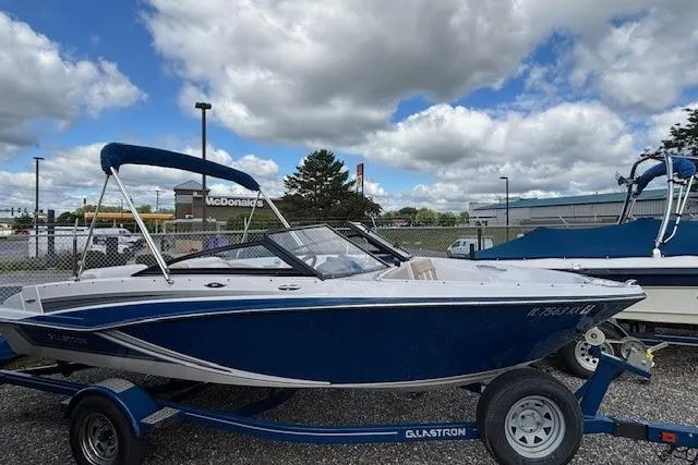 Slide: The Image of 2018 Glastron GT 187 boat on trailer, parked outdoors under cloudy sky. - 16