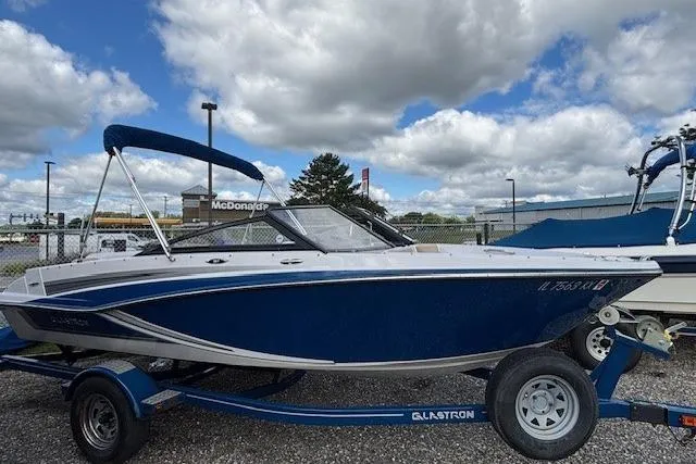 Slide: The Image of 2018 Glastron GT 187 boat on trailer, blue and white, parked outdoors. - 3