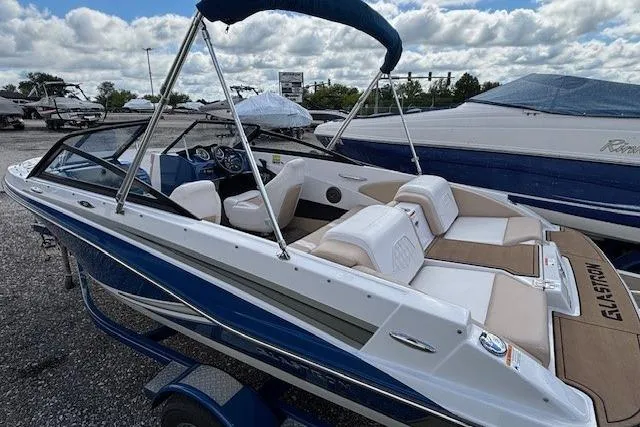 Slide: The Image of 2018 Glastron GT 187 boat with blue and white exterior, parked outdoors under cloudy sky. - 4