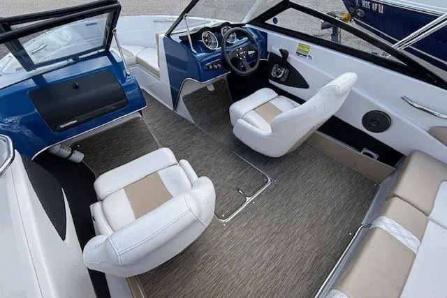 Slide: The Image of 2018 Glastron GT 187 boat interior with white and beige seating, blue dashboard, and steering wheel. - 7