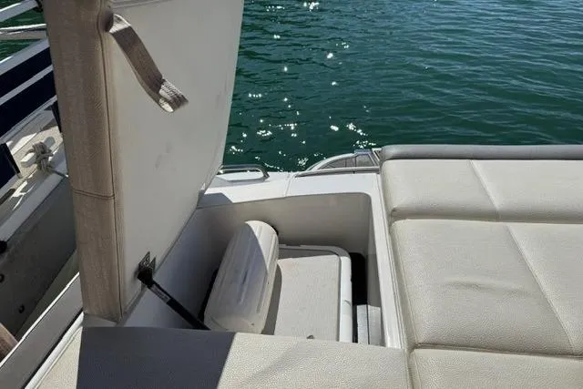 Slide: The Image of 2017 Cobalt 220S boat with open storage compartment, beige seating, and water in the background. - 14