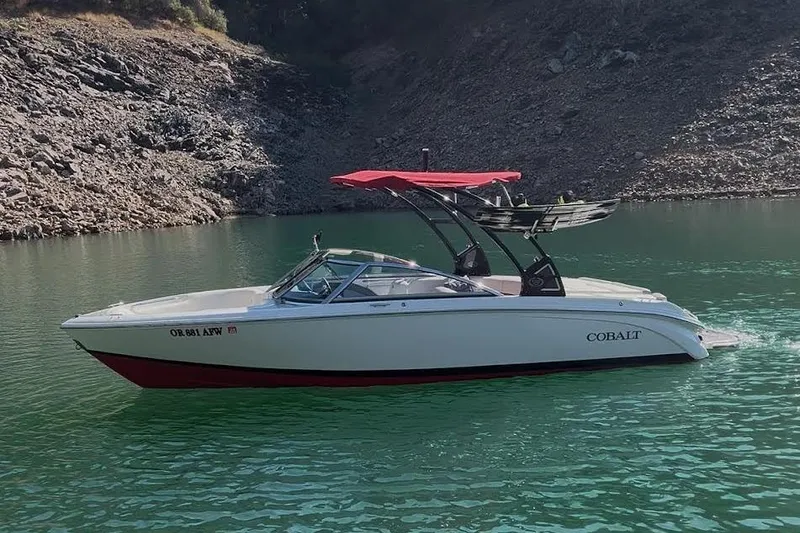 Slide: The Image of 2017 Cobalt 220S boat with red canopy on a serene lake. - 2