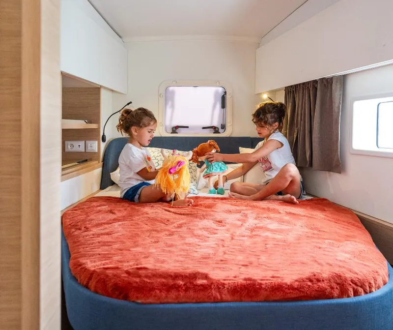 Slide: The Image of Children playing with dolls on a cozy bed inside a 2025 Fountaine Pajot NEW 41 yacht. - 26