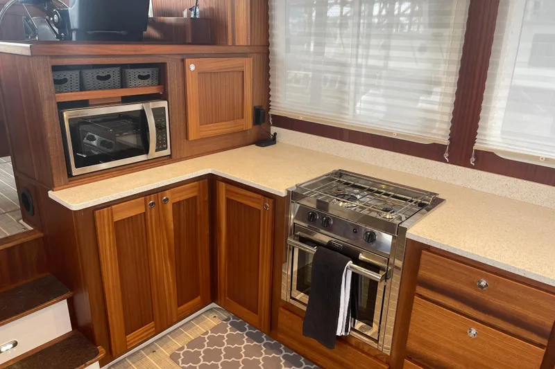 Slide: The Image of 2022 American Tug 362 kitchen with wood cabinetry, microwave, and stainless steel stove. - 10