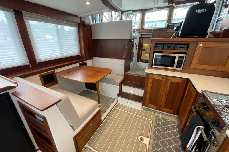 Slide: The Image of Interior of 2022 American Tug 362, featuring dining area, kitchen, and helm station. - 13