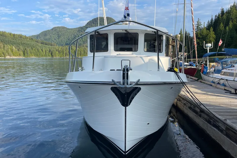 Slide: The Image of 2022 American Tug 362 docked in a scenic, forested marina. - 2