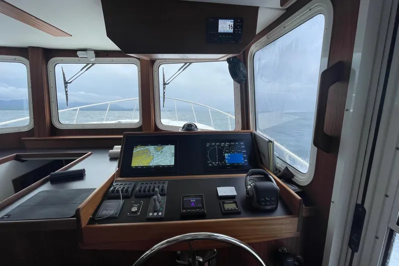 Slide: The Image of American Tug 362 (2022) helm with navigation screens and ocean view through windows. - 24