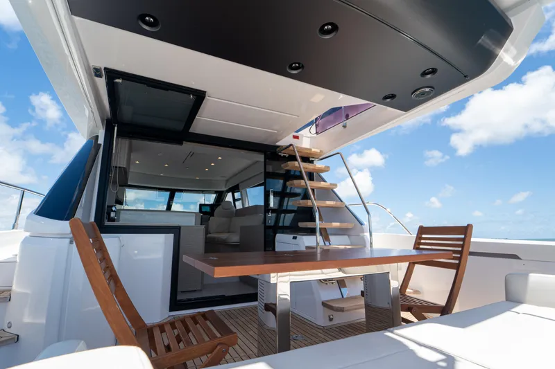 Slide: The Image of Luxurious 2022 Ferretti Yachts 500 deck with wooden chairs and table under blue sky. - 22