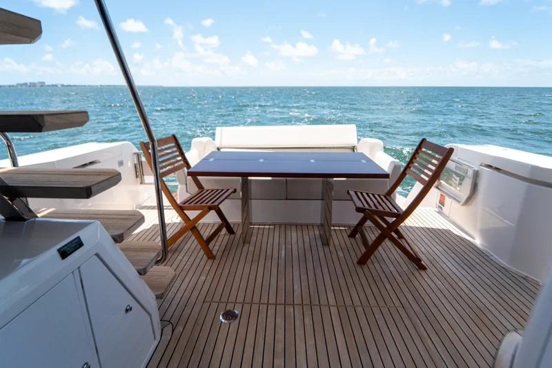 Slide: The Image of 2022 Ferretti Yachts 500 deck with wooden chairs and table, ocean view. - 23