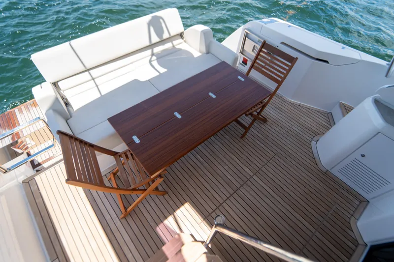 Slide: The Image of Deck of 2022 Ferretti Yachts 500 with wooden table and chairs, overlooking the sea. - 52