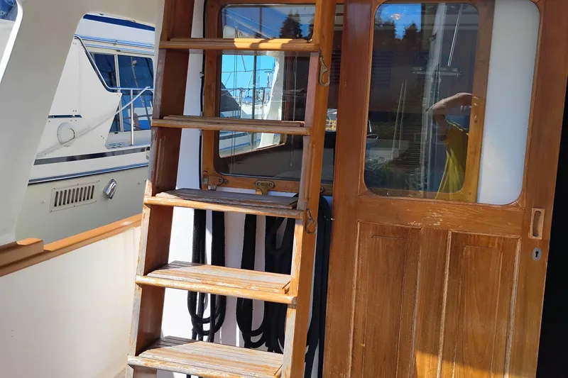 Slide: The Image of 1978 Puget 38 Europa Trawler with wooden ladder and door, docked at marina. - 12