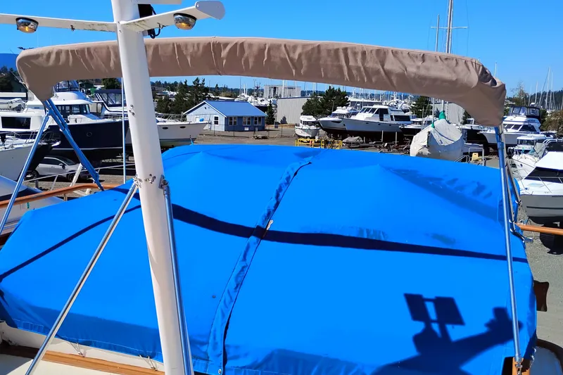 Slide: The Image of 1978 Puget 38 Europa Trawler with blue cover in marina setting. - 14