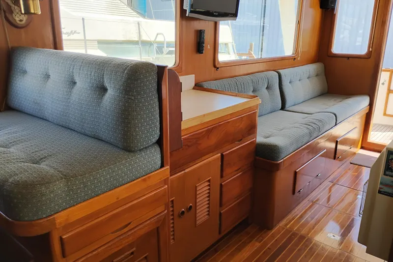 Slide: The Image of 1978 Puget 38 Europa Trawler interior with cushioned seating and wooden cabinetry. - 25
