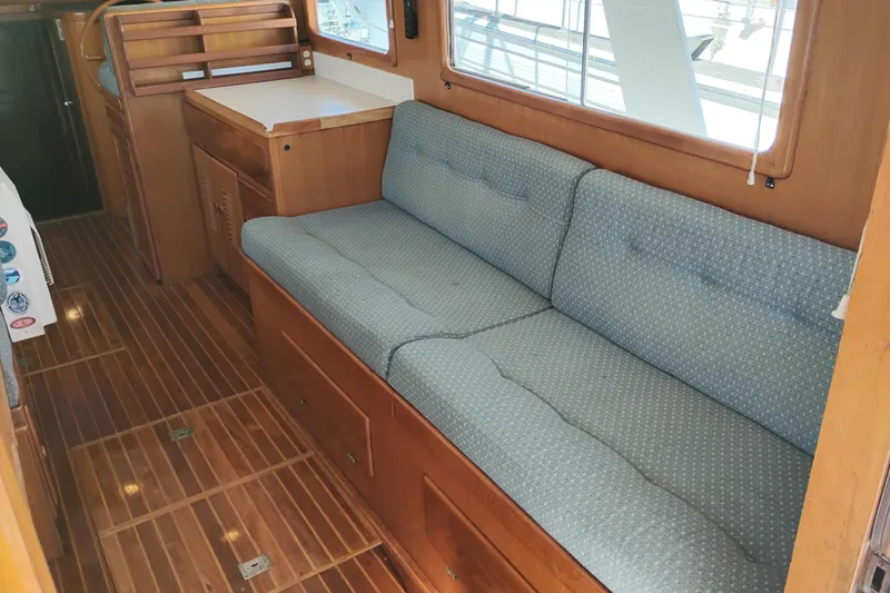 Slide: The Image of 1978 Puget 38 Europa Trawler interior with wooden flooring and cushioned seating. - 27
