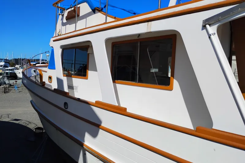 Slide: The Image of 1978 Puget 38 Europa Trawler with white hull and wooden accents in a marina. - 3