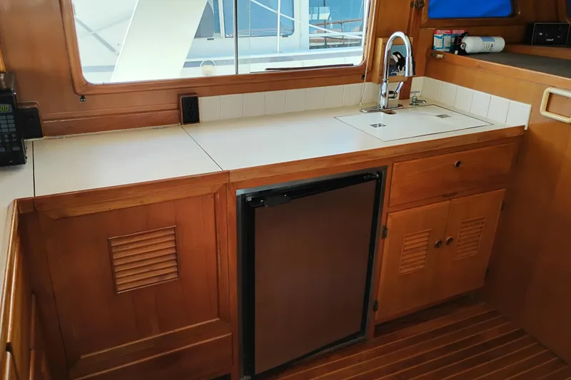 Slide: The Image of 1978 Puget 38 Europa Trawler kitchen with wooden cabinets, sink, and mini fridge. - 31